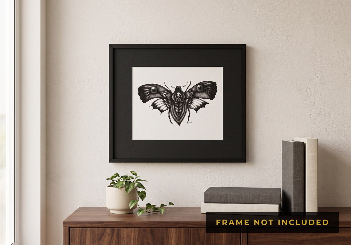The Death's Head Moth print framed in black, hanging above a wooden sideboard