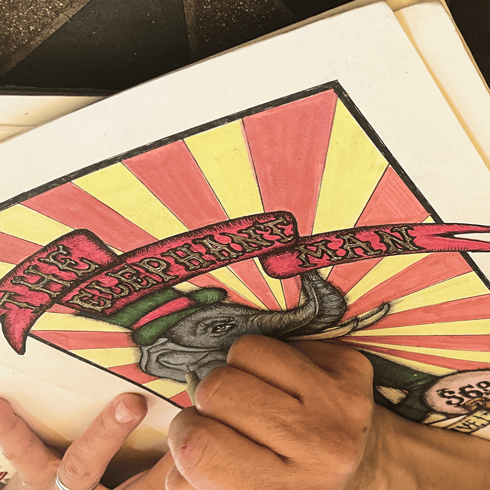 The elephant's head being inked by hand, the lettered ELEPHANT MAN ribbon already finished