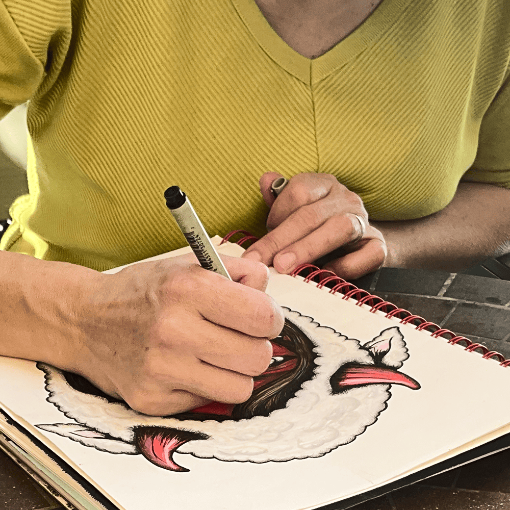 Maria Keller drawing Mama Shilli by hand in a spiral-bound sketchbook