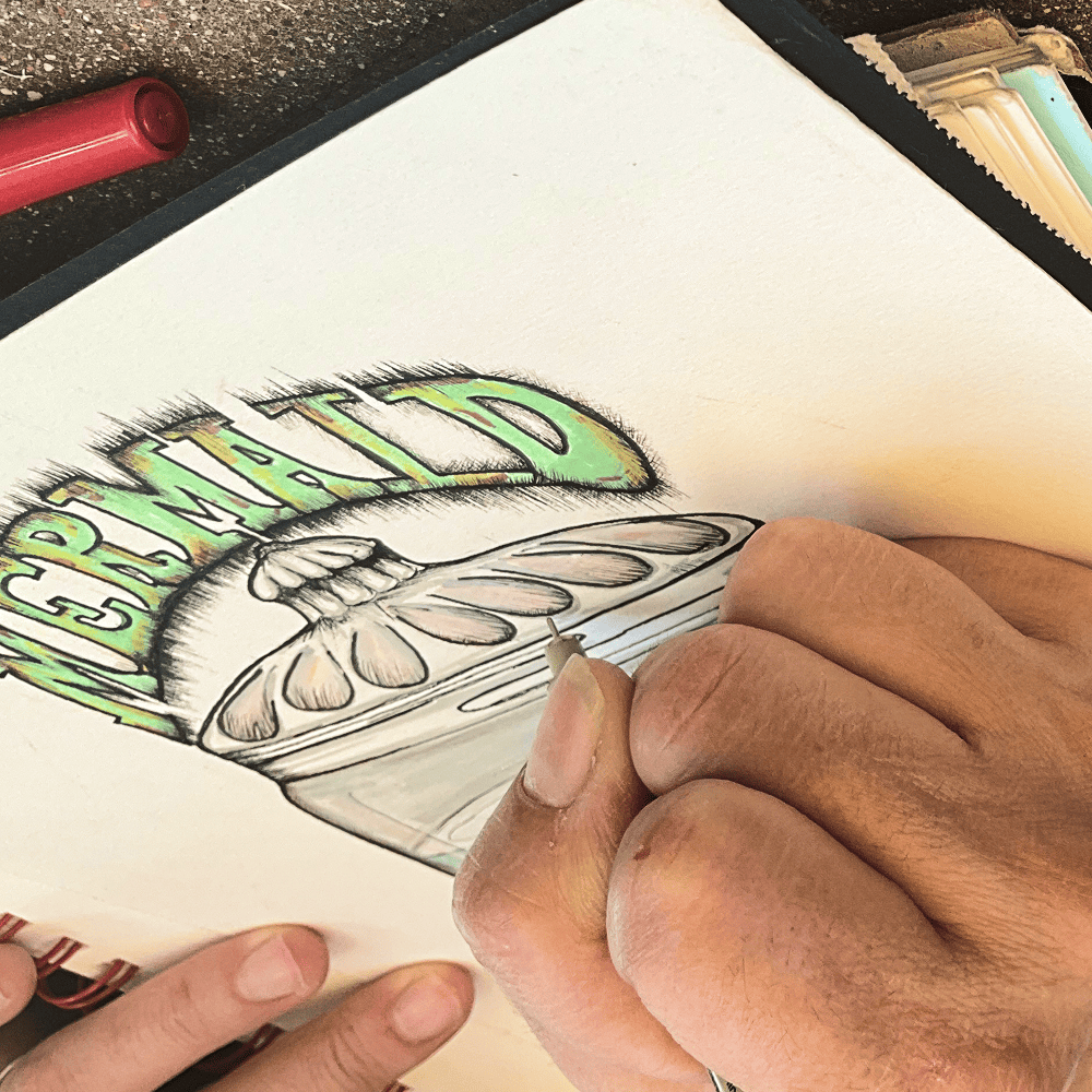 Inking the lid of the specimen jar beneath the hand-lettered MERMAID title